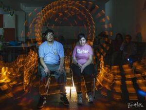Dos participantes del CAI ASPAYM posan rodeados de trazos de luz en una fotografía de larga exposición