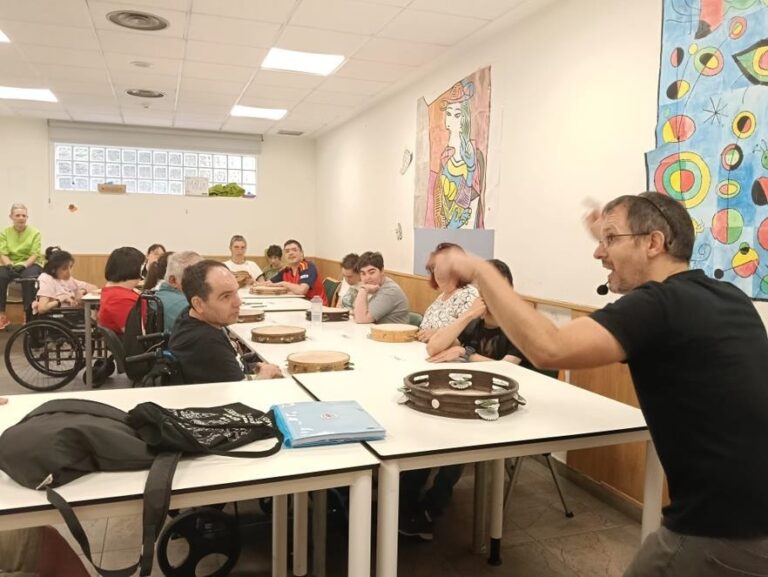 Ramsés Ilesies explica distintos toques de pandereta durante el taller con las personas usuarias del CAI ASPAYM.