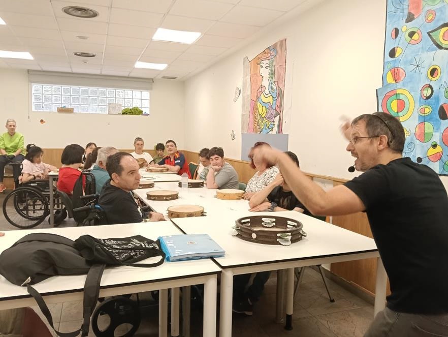 Ramsés Ilesies explica distintos toques de pandereta durante el taller con las personas usuarias del CAI ASPAYM.