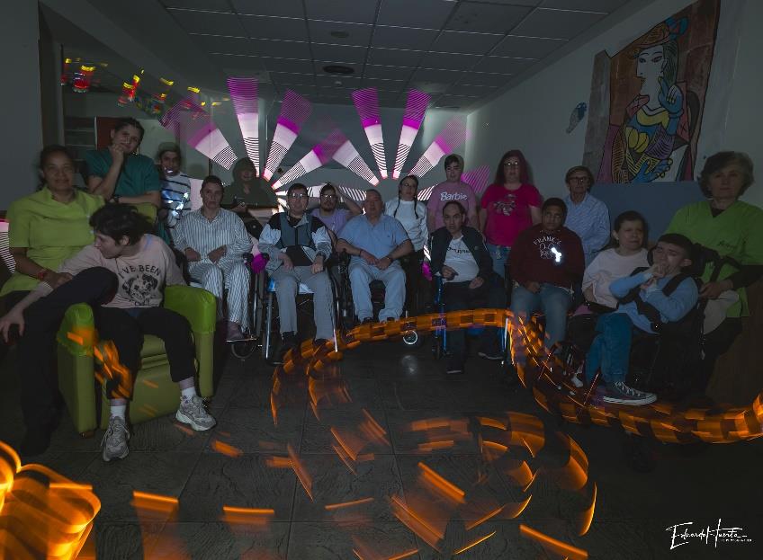 Participantes del CAI ASPAYM posan en grupo durante un taller de pintura con luz.